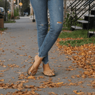 Female model wearing The Trenza  leather flip flop sustainably made with upcycled tire soles by  Brave Soles in caramel color. 