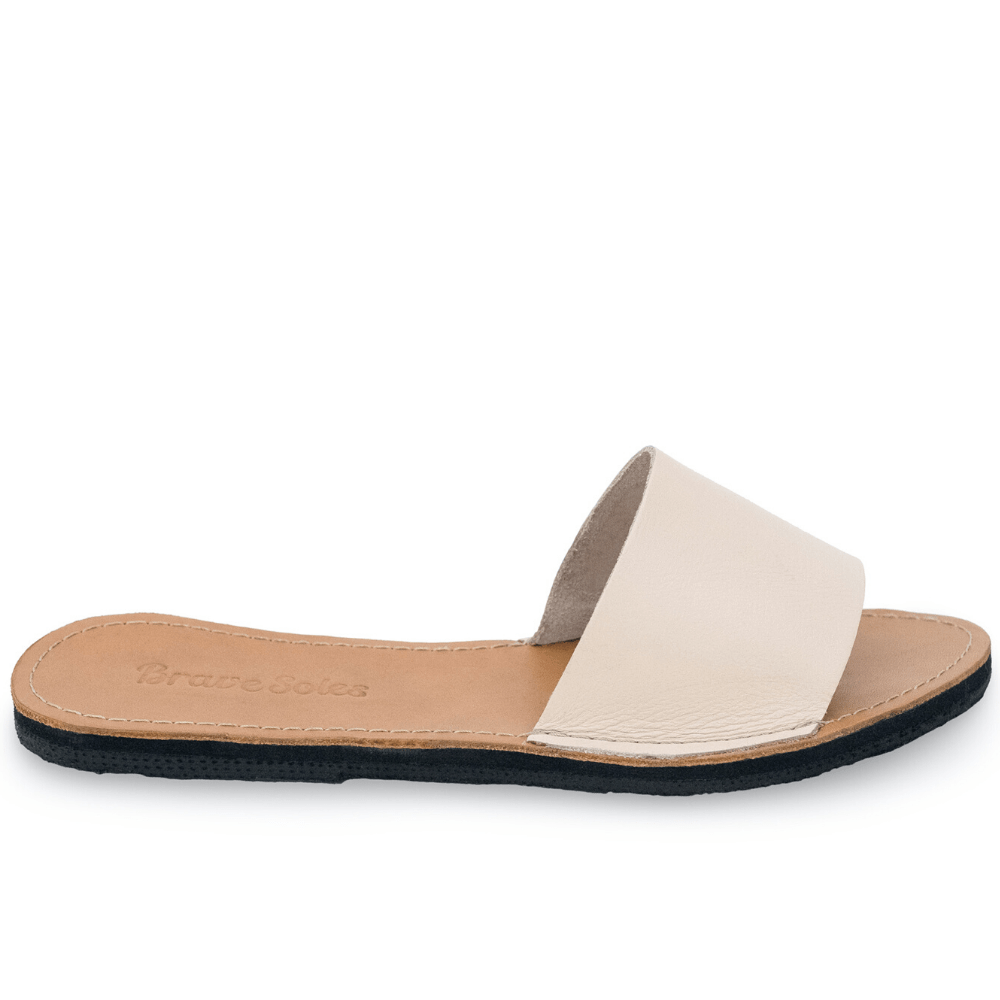 Side view of The Linda Women's Leather Slide Sandal in ivory and natural color, sustainably made by Brave Soles.